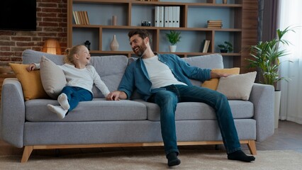 Happy caucasian family falling down on couch at own home father with daughter celebrate moving day relocation funny dad with child kid girl jumping on soft break relaxation resting playing laughing