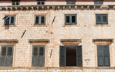 Green louvered window shutters on stone facade