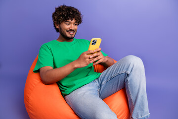 Young man in casual outfit on a bean bag using a smartphone in vibrant surroundings
