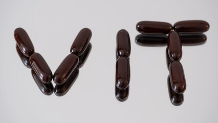 Word VIT made of softgel capsules on reflective surface