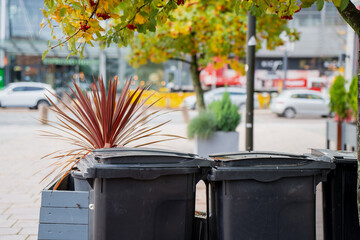 Urban waste management containers on modern city street with organized recycling bins and...