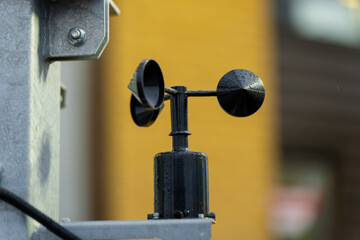 Black cup anemometer mounted on metal frame measuring wind speed, representing meteorological instrumentation, environmental monitoring technology and precision weather data collection equipment