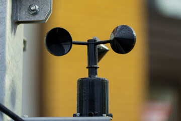 Black cup anemometer sensor mounted on metal pole for measuring wind speed, representing meteorological instrumentation, environmental monitoring technology and precision weather data collection syste