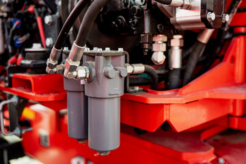 Hydraulic filter assembly with connected hoses and fittings mounted on red machinery frame showing oil filtration system for hydraulic pressure control and maintenance of industrial equipment