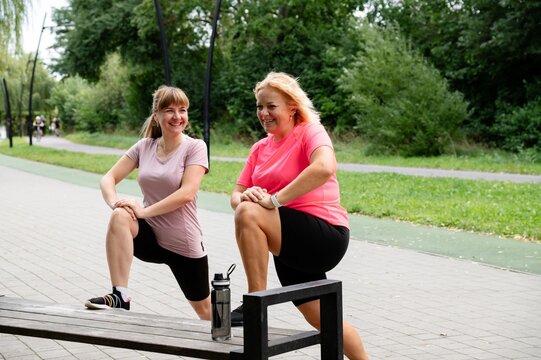 Friends enjoy outdoor fitness with diverse body types while exercising in the park during a sunny day