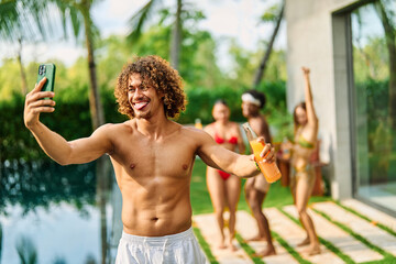 Young people having fun dancing and drinking and bonding listening to music at a party by pool in a villa or resort, Young people enjoying vacation in a tropical resort hotel, young man dancing and ta