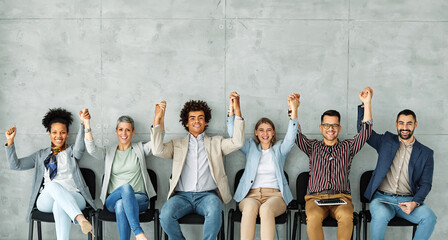 Group of young businss people sitting in chairs and waiting for an interview holding hands together