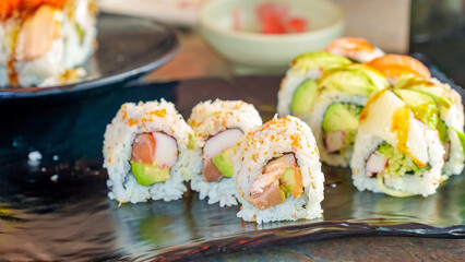 Colorful sushi rolls arranged on a black plate, showcasing fresh ingredients and vibrant presentation, perfect for culinary enthusiasts and food lovers