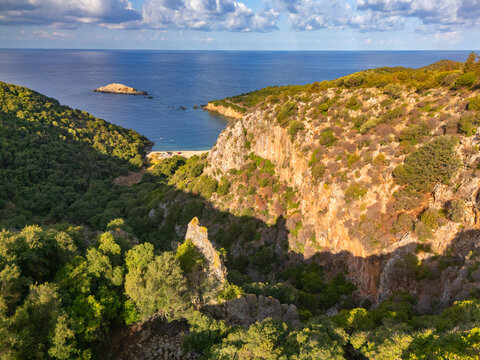 Aerial view of the rugged coastline meets the turquoise Ionian Sea near Ierousalim beach, a symphony of green vegetation and golden cliffs, Ierousalim, Kefalonia, Greece.