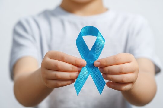 Child with blue ribbon against white backdrop Support symbol for men s cancer awareness in November Room for text