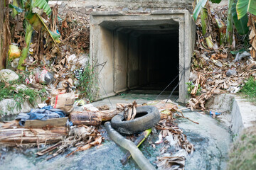 dirty exit point of the drainage channel with rubbish and car tires © ozzuboy