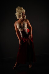 Full length portrait of beautiful woman in a red evening dress and a white wig on a black background
