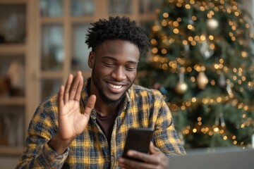A young Black man video chatting by a Christmas tree at home