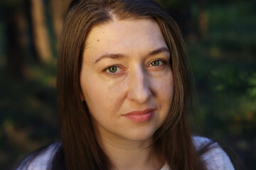 Close up portrait of a young dark haired woman with light eyes with natural expression and warm...