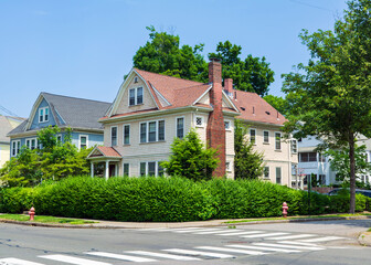 Naklejka premium Beautiful two-story family house with tall brick chimney and lush green hedge in Newton, Massachusetts, USA 