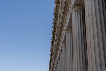 Close-up view of classical marble columns in the Ancient Agora of Athens, Greece. Captures the elegance and symmetry of ancient Greek architecture under a clear blue sky.