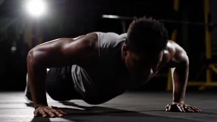 Athletic African American man performing push-ups with focus in a gym setting - Powered by Adobe