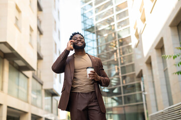 Obraz premium Black business man walking talking on phone drinking coffee