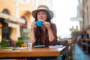 Woman enjoying coffee at cafe street table during travel