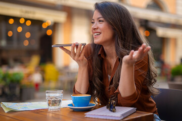 Woman using smartphone speakerphone having outdoor cafe conversation
