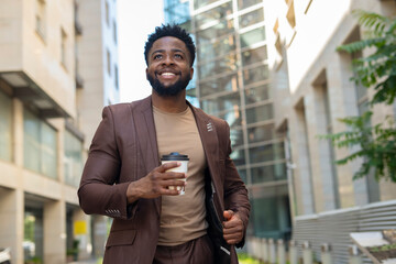 Naklejka premium Smiling black business man walking in city street