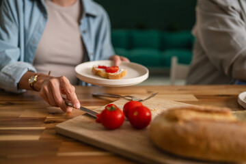 Couple enjoying breakfast together preparing fresh toast with tomatoes