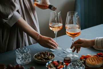 Pouring rose wine with classic snacks of cheese, bread and olives. Party or anniversary celebration.