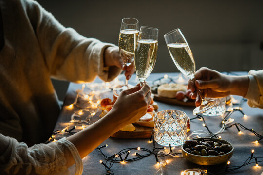 Friends celebrating Christmas or New Year eve party with champagne or sparkling wine.
