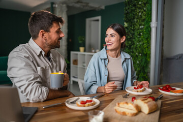 Happy couple enjoying breakfast together at home kitchen