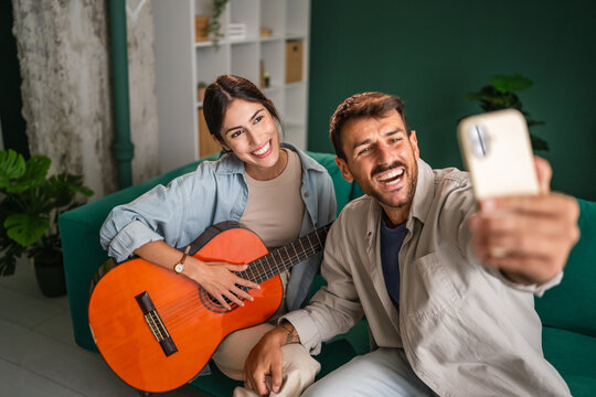 Happy young couple taking selfie with guitar