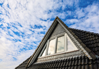 House roof dormer window contrasting blue sky