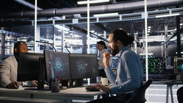 Data center system administrator talking with coworker in office while doing software updates. Server room IT expert and colleague chatting, optimizing infrastructure rackmounts configuration, camera