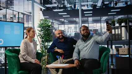 Multiethnic business people seal their partnership with a picture on social media, reaching a verbal agreement for a new international collaboration. CEOs taking photos on media platforms. Camera A.