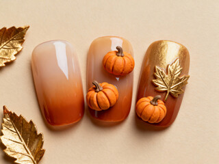 Elegant autumn nail art design with tiny pumpkins and golden leaves on warm gradient background