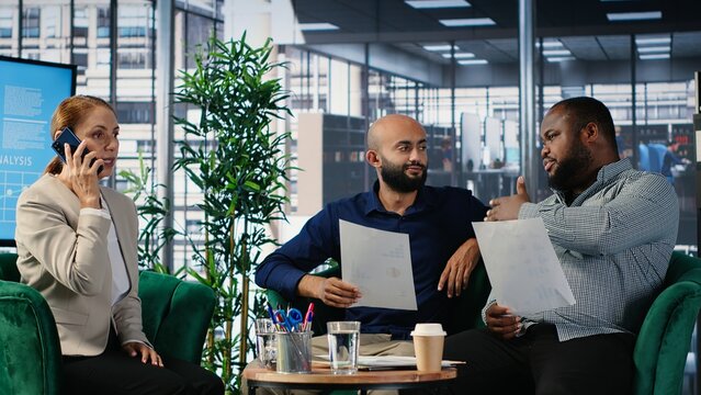 Woman business leader interrupting a meeting for an insightful phone call, discussing some important details on the telephone line. Diverse ambitious CEOs during a conference. Camera B.