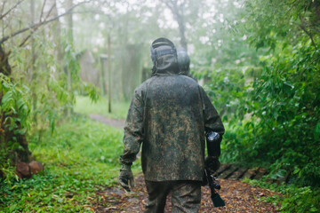 Fototapeta premium Paintball game, team in camouflage protective uniform with paintball guns and ammunition, strikeball arena battlefield, paintballer aiming and shooting at opponents, airsoft players match tournament