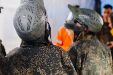 Paintball game, team in camouflage protective uniform with paintball guns and ammunition, strikeball arena battlefield, paintballer aiming and shooting at opponents, airsoft players match tournament