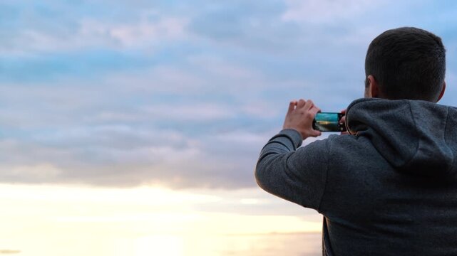a man photographs the sunset or takes a video on the sea on the phone