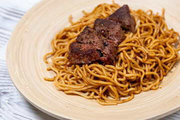 Sliced Steak on Soy-Sauce Noodles on a Wooden Plate
