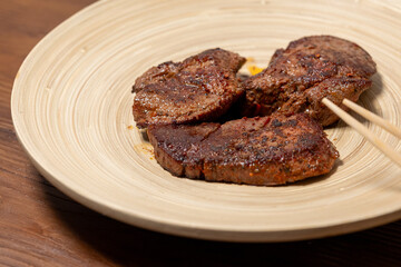 Close-Up of Spice-Seasoned Steak Served on a Wooden Plate with Chopsticks

