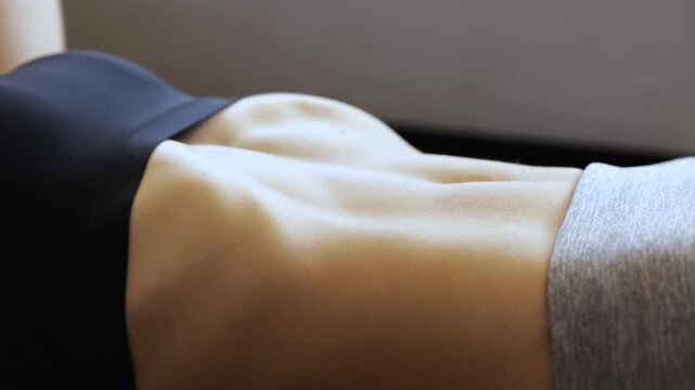 Young woman has workout at home during quarantine. Doing abs exercise with lying on floor. Muscles working. Sexy body moving. Slow down camera.