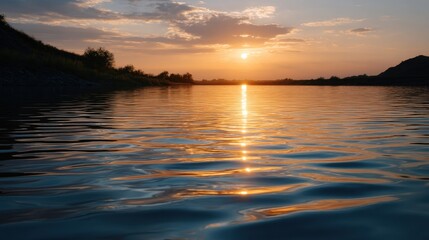 Obraz premium Serene Sunset Glow Reflecting on Calm Water with Gentle Ripples in the Background