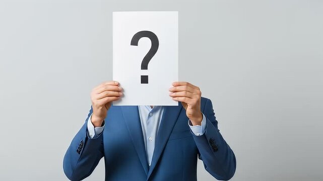 Man in blue suit holding a question mark sign over his face	