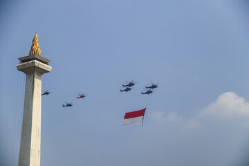  jakarta, Indonesia - October 5 2025. Military helicopters flying past the National Monument in Jakarta, proudly carrying the Indonesian flag at Indonesian Armed Force day. editorial use