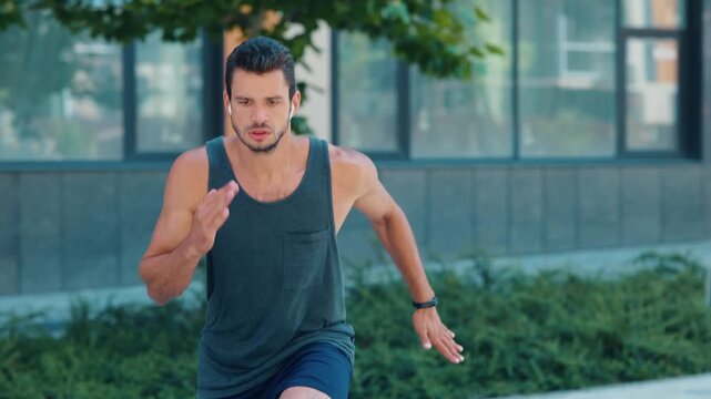 Young man exercising outside. Guy cheking time and stanrt running very fast on the same place. Man training muscles and power. Exercising outside. Urban view.