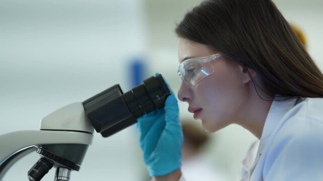 A pathologist in a hospital lab examines a stained tissue specimen under a microscope, identifying cellular abnormalities to provide a definitive diagnosis for a patient's condition.