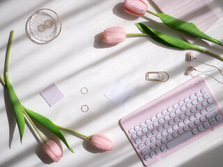 A feminine and cute computer desk with sunlight streaming in, flat lay top view, concept of a happy, light-filled everyday life