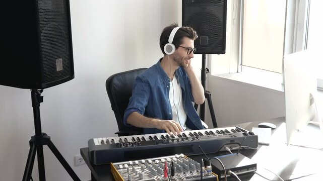 Young man in sound recording studio. Guy sit at table and work with music mixing console and computer. Recording music at home.