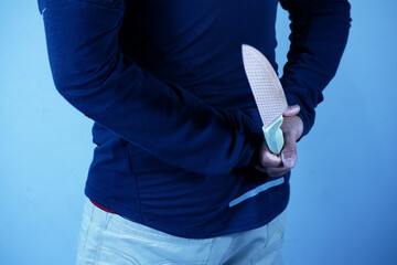 Thief hiding knife behind his back, man holding weapon with hand, close-up, armed attack concept. Man with the knife. Hand with a knife behind his back. Criminal with knife weapon hidden behind his ba