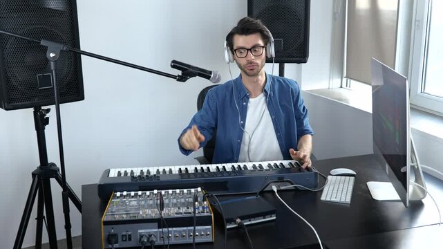 Young man in sound recording studio. Guy greets and start working with adjusting sound console. Professional music equipment.
